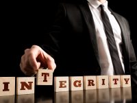 Close up Businessman Arranging Small Wooden Pieces with Integrity Letters on Black Background.